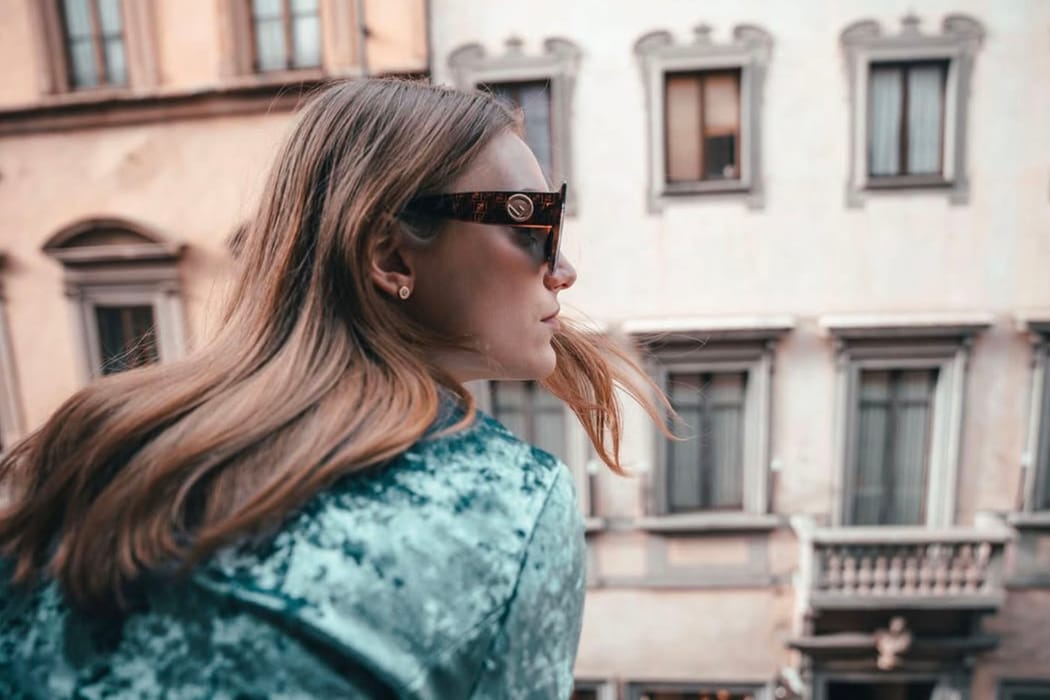 Chica con gafas de sol mirando desde el balcón